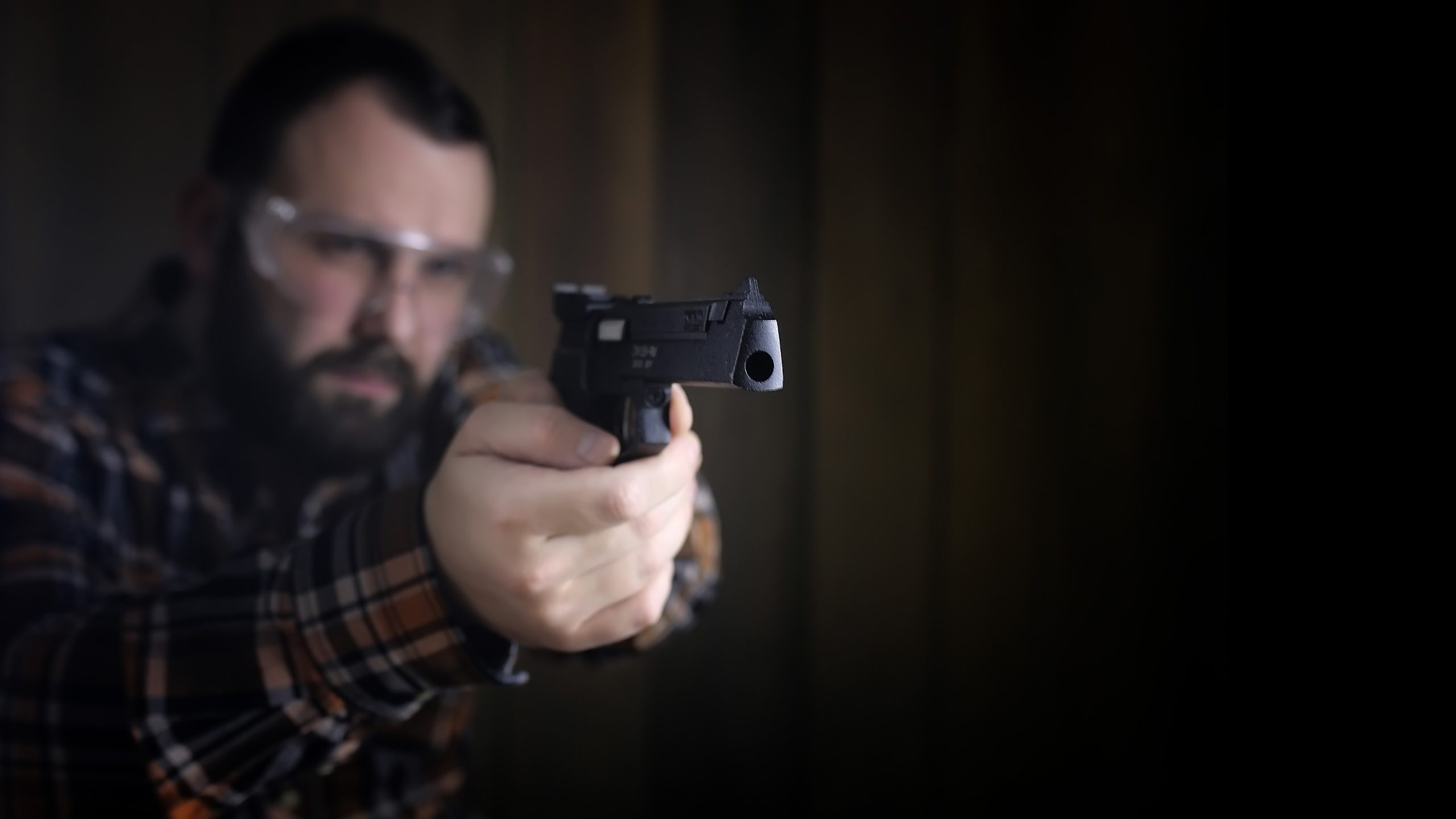man with put on protective goggles and ear training in pistol shooting